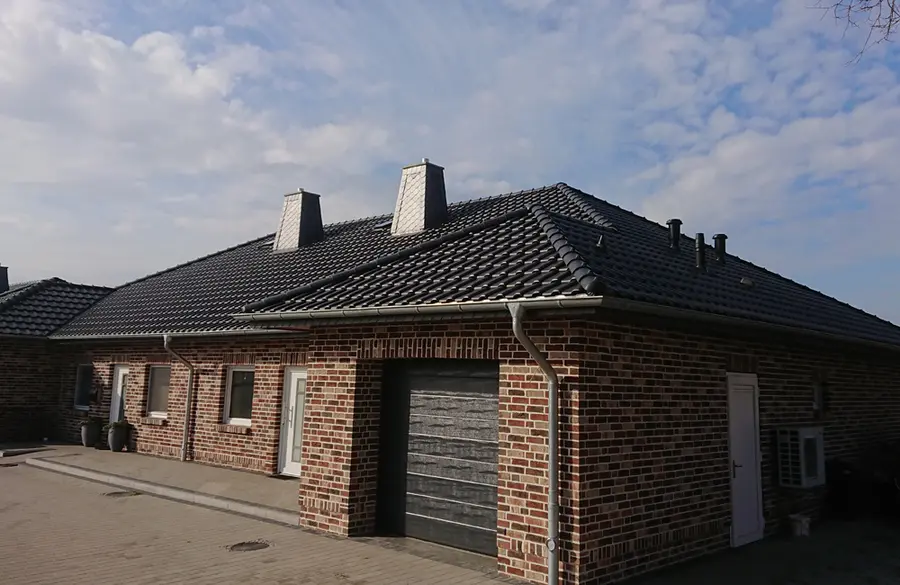 Neubau Doppelhäuser mit Walmdach, dunkle Dachpfannen, Schornsteinverkleidung, Zinkdachrinnen.